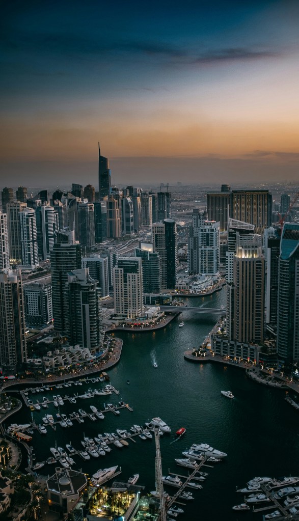 Luxury superyachts docked at Dubai Marina with the city skyline and Palm Jumeirah in the background during golden hour